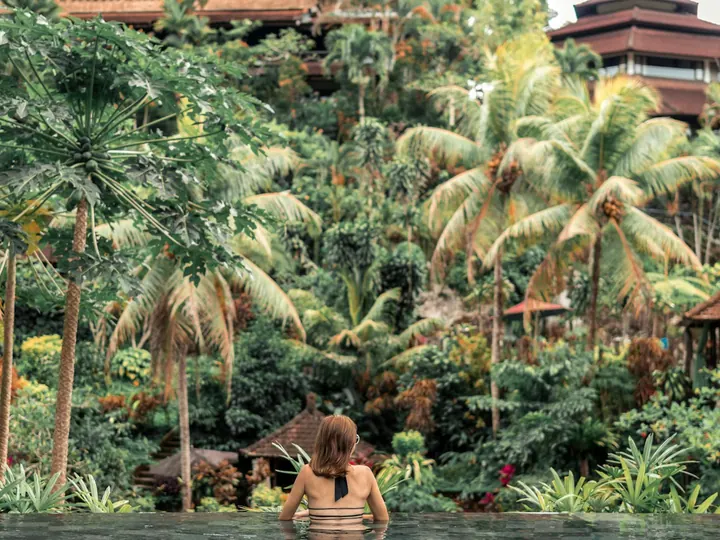 Woman in an infinity pool overlooking the Bali jungle
