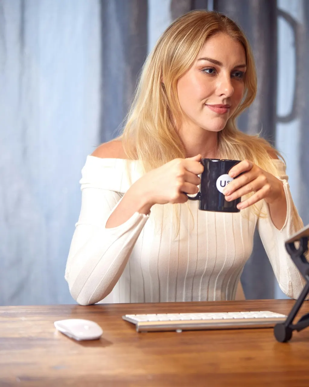 Woman working on a laptop at a desk with a coffee mug