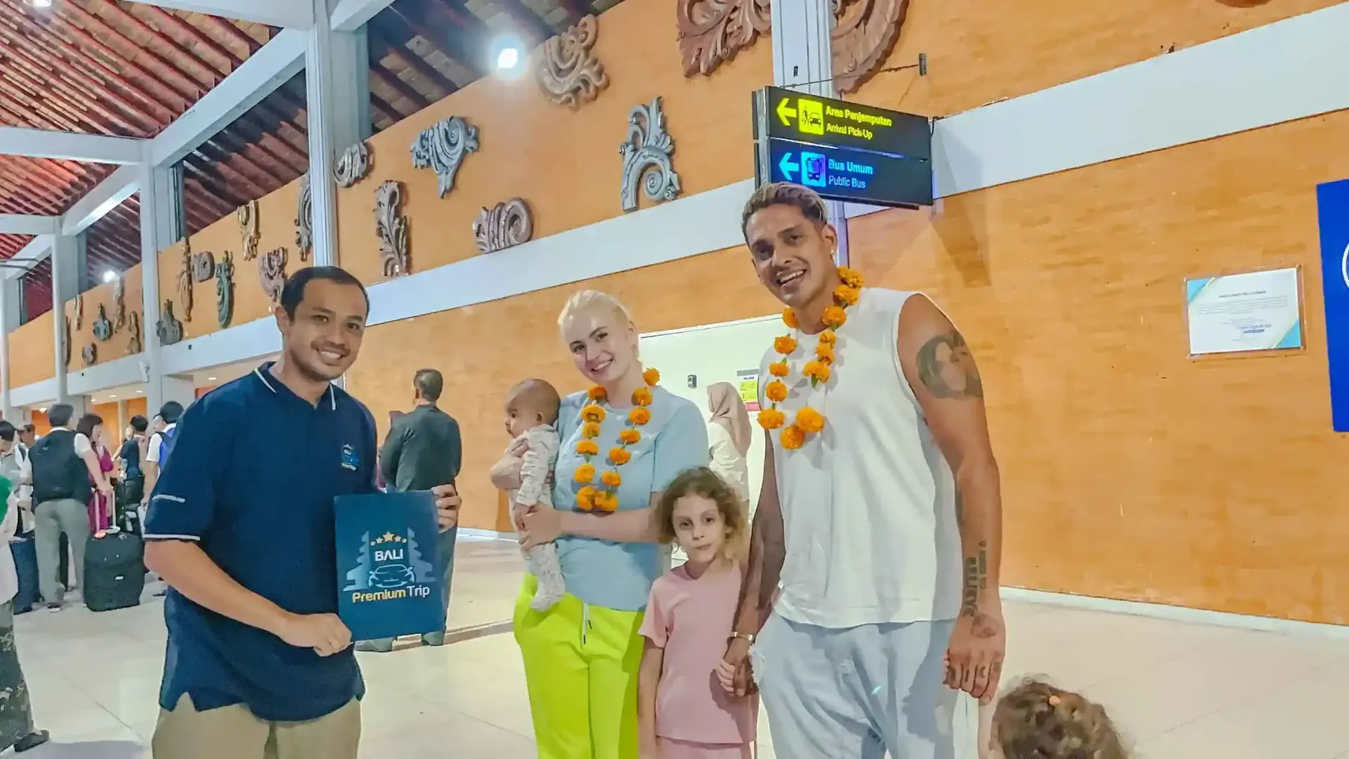 Bali Premium Trip agent welcoming a family with flower garlands at Ngurah Rai Airport arrivals